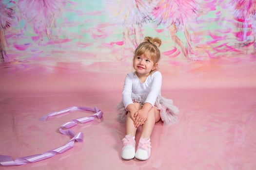 A little girl sitting on a pink floor with a pink background photo