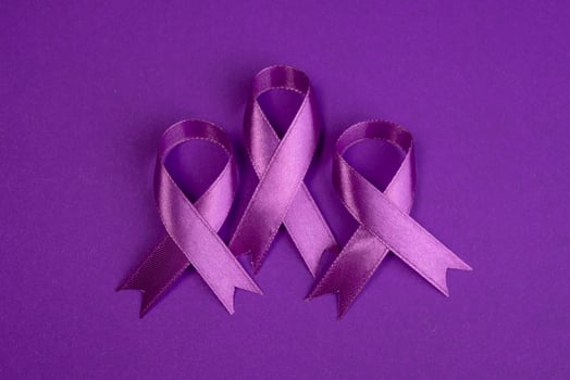 Three purple ribbons lying on a purple surface. Cancer awareness background photo