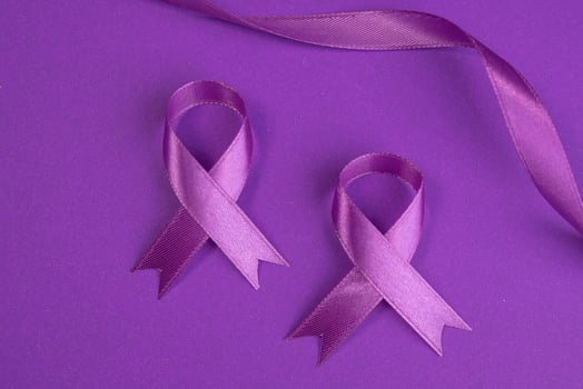 Two purple ribbons lying on a purple background. Cancer awareness cpncept photo