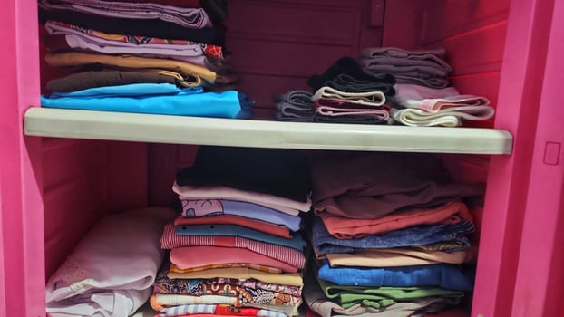 a pink storage cabinet with many folded clothes photo