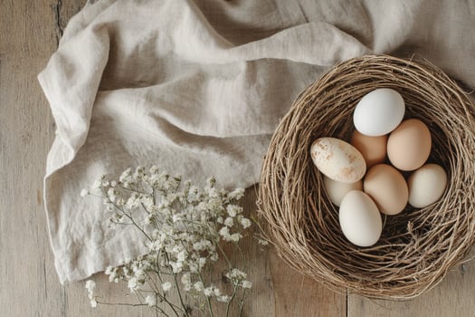 A cozy rustic Easter setting featuring pastel eggs in a woven nest, surrounded by soft linen and delicate wildflowers. A perfect composition celebrating natural beauty and warmth. photo