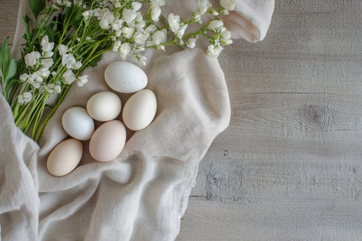 A gentle Easter composition with speckled eggs surrounded by wildflowers and textured fabric. The soft lighting enhances the organic elements, creating a timeless and rustic holiday scene. photo