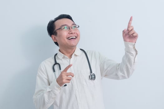 joyful Asian man doctor, male nurse pointing up pose isolated white background. photo