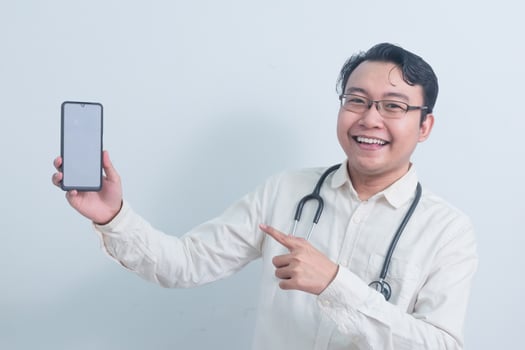 joyful Asian man doctor, male nurse Pointing and showing phone isolated white background. photo