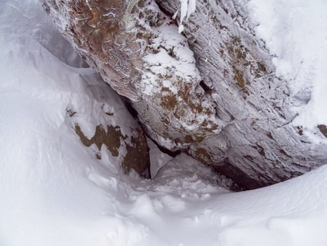 The den, the hole is covered with snow. Hole under a large granite boulder. photo