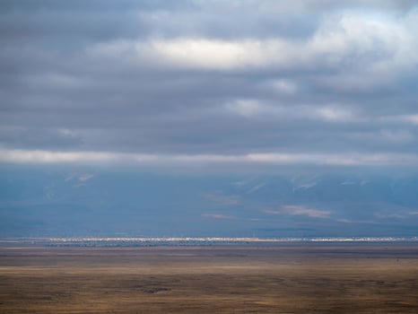 Thin line of a distant city in the steppe under a blue cloudy sky. Altai steppe. photo