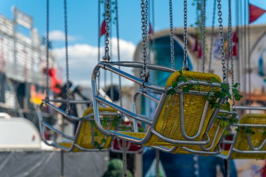 Swinging seats hang in bright sunlight at a bustling amusement park during summer festivities photo