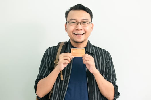 Happy Asian Student hold credit card. School, Banking, Financial isolated background, blue concept. photo