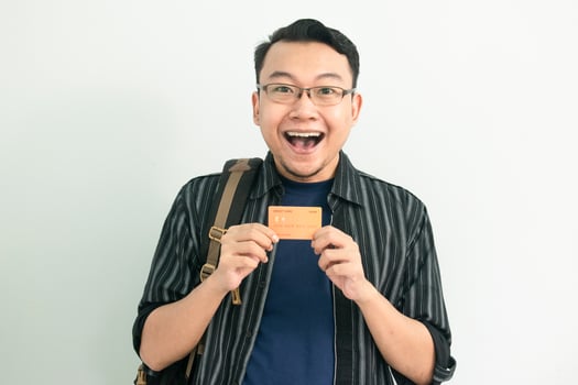 Shocked Asian Student hold credit card. School, Banking, Financial isolated white background photo