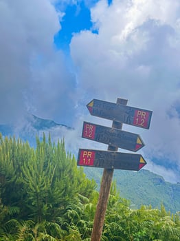Madeira island PR1 Pico do Arieiro hiking trail sign famous place road route valley path fog mist green grass eco nature connection dramatic sky mountains challenge achievement vertical photo