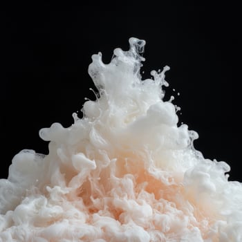 Abstract white and peach ink swirling in water, black background photo