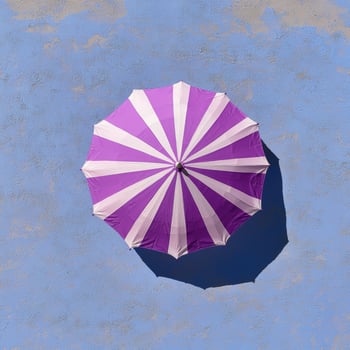 Purple and white striped umbrella on a blue wall photo
