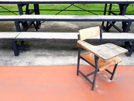 Old school desk putting outdoor in sport field with amphitheater or seat background and left copy space. Damaged object concept. photo