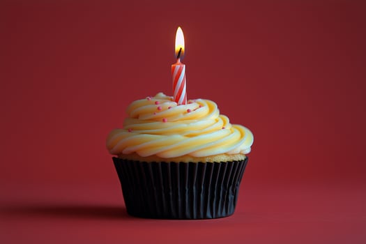 Delicious cupcake with frosting and candle on red background celebrates special occasion photo