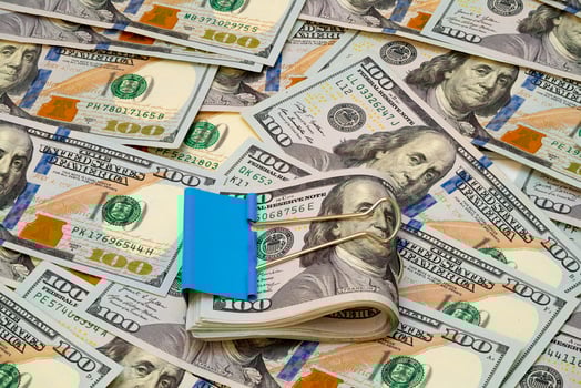 Stacks of cash secured with a binder clip on a bed of dollar bills photo