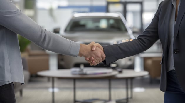 Two people shaking hands in front of a car dealership photo