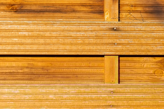 Wood paneling with warm tones and textured lines in a natural setting during daylight hours photo