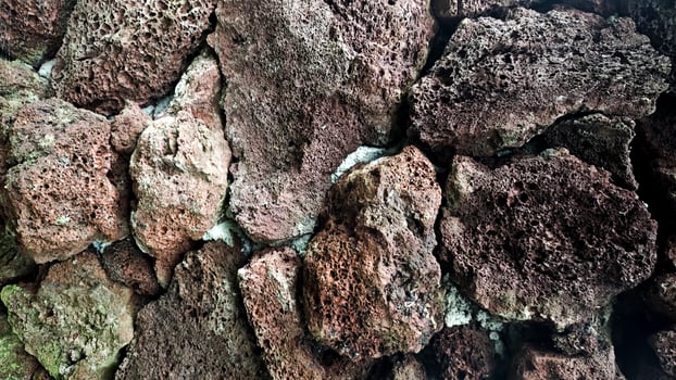 Close-Up of Rough Volcanic Rocks with Textured Surface in Natural Earthy Colors Forming a Unique Stone Wall Background photo