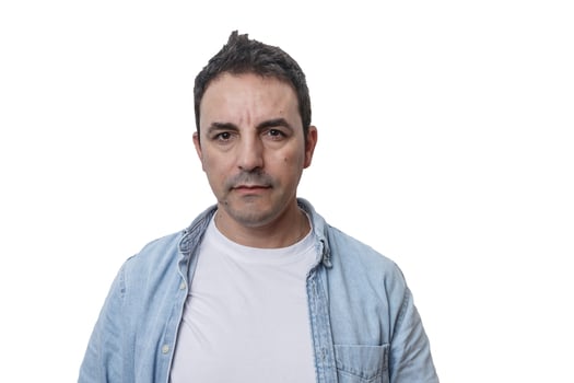 Man with short dark hair wearing a light denim jacket and white shirt against a plain white background photo