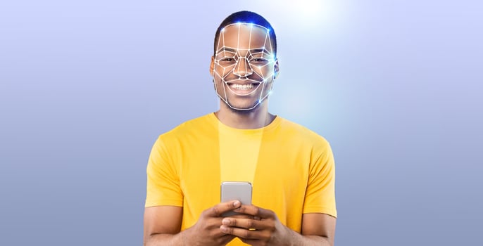 A young man with a cheerful expression uses his smartphone to engage in face recognition technology. The background is a simple gradient, emphasizing the modern tech experience. photo