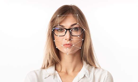 A woman with glasses is featured against a plain background, showcasing a facial recognition overlay highlighting key facial features. This technology emphasizes identification capabilities. photo