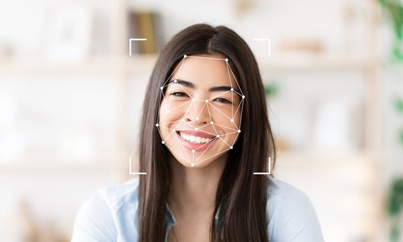 A smiling woman with long dark hair is featured in a well-lit indoor space. Facial recognition technology is visible, highlighting key facial features. photo