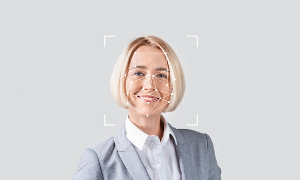A professional woman smiles as facial recognition technology analyzes her features in a minimalistic setting. The soft background emphasizes the focus on identification processes. photo