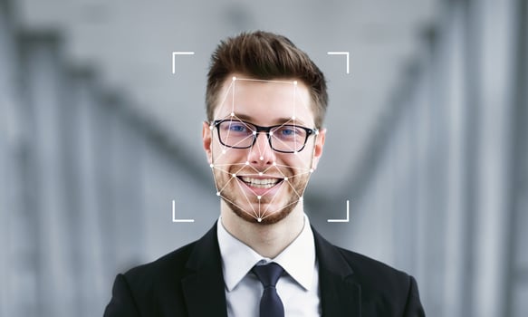 A man in formal attire smiles while facial recognition software identifies him. The background features soft architectural lines, enhancing the focus on identification technology. photo