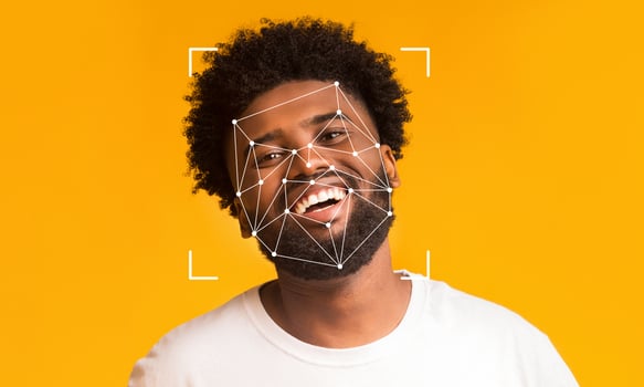 A joyful man with curly hair smiles against a bright yellow backdrop. Overlayed are facial recognition markers, illustrating the use of identification technology in everyday life. photo