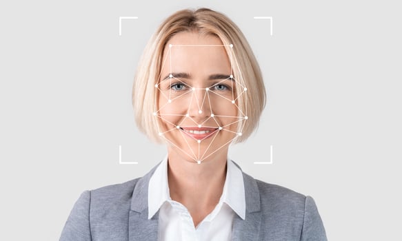A woman with blonde hair smiles confidently while facial recognition technology analyzes her features. The setting has a light, empty background, emphasizing the subject and technology. photo