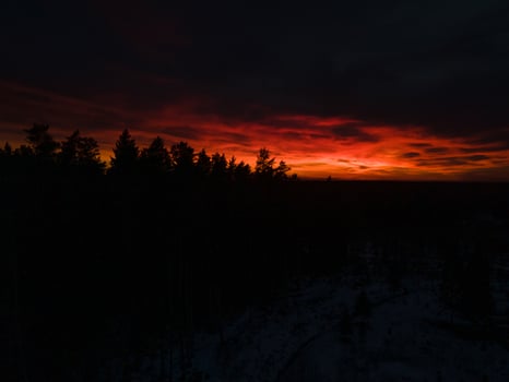 Dramatic Sunset with Vibrant Red and Orange Sky Over Snowy Ground photo