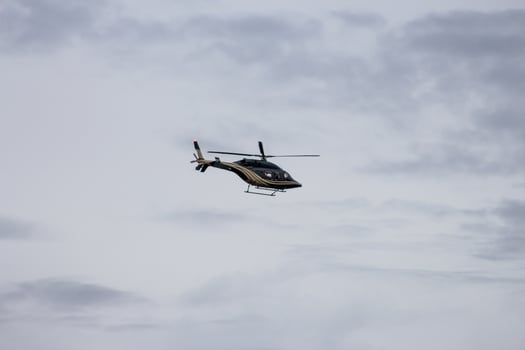 Black and Gold Helicopter in Flight Against a Cloudy Sky photo