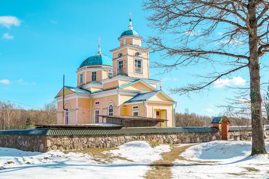 Yellow Church with Blue Domes and Crosses in a Snowy Rural Setting photo