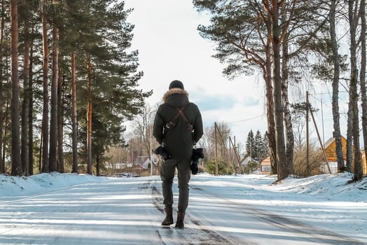 Person Walking on Snow Covered Road in Rural Winter Landscape photo