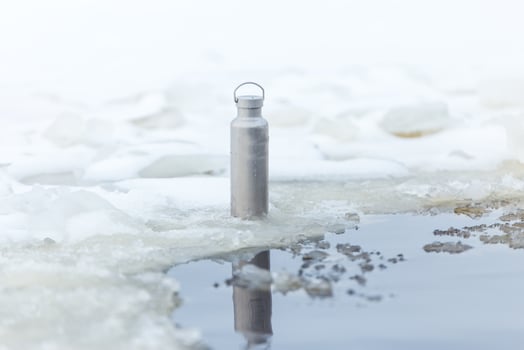Metallic Water Bottle on Ice Near Partially Frozen Water photo
