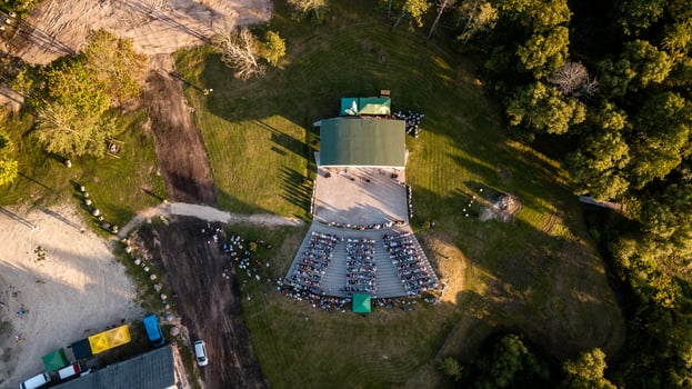 Aerial View of Outdoor Amphitheater with Green Roofed Stage and Attendees photo