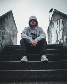 Man sits on urban stairs, graffiti background, contemplative pose, stock photo