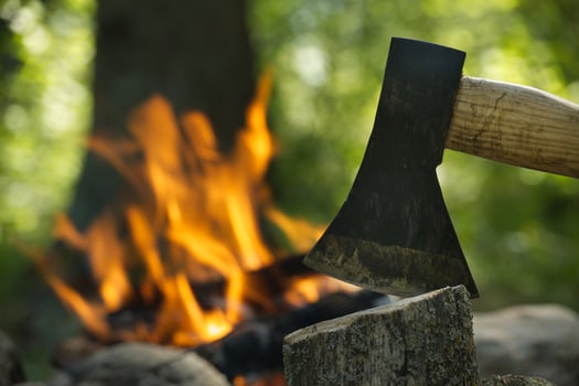 Axe splitting firewood in front of bonfire in forest photo
