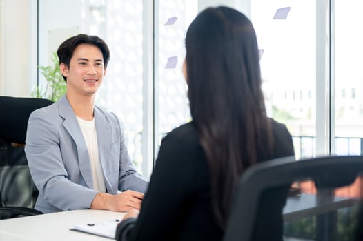 A confident and friendly Asian businessman or CEO is interviewing a female candidate in his office. photo