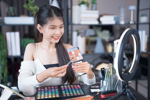 beauty blogger is holding a phone and looking at her makeup photo
