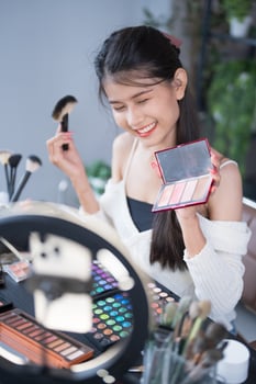 beauty blogger is holding a makeup palette and looking at it photo
