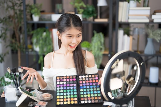 beauty blogger holding a makeup palette and looking at the camera photo