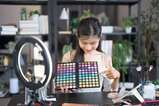 beauty blogger woman is holding a makeup palette and pointing at it photo