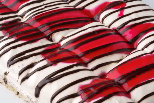 Delicious dessert featuring layers of cream, chocolate, and cherry sauce at a bakery photo