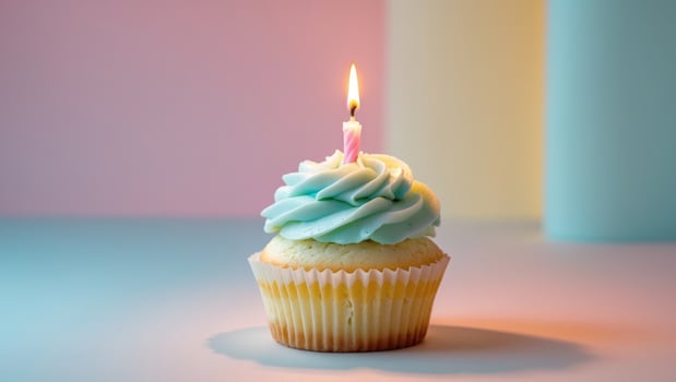 Colorful cupcake topped with frosting and a lit candle on a pastel background for a festive celebration. photo