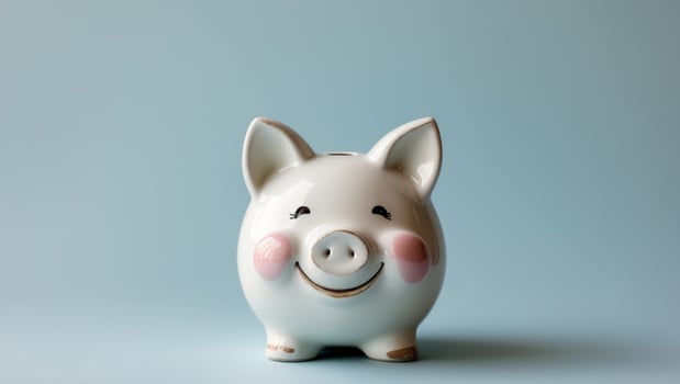 Cute ceramic piggy bank with a smiling face and rosy cheeks on a light blue background. photo