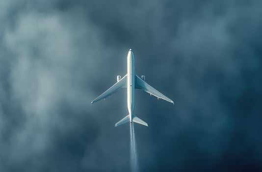 Airplane flying above clouds during day, showcasing contrail in serene blue sky photo