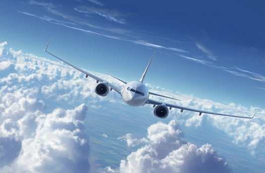 Airplane flying above fluffy clouds during bright daylight photo