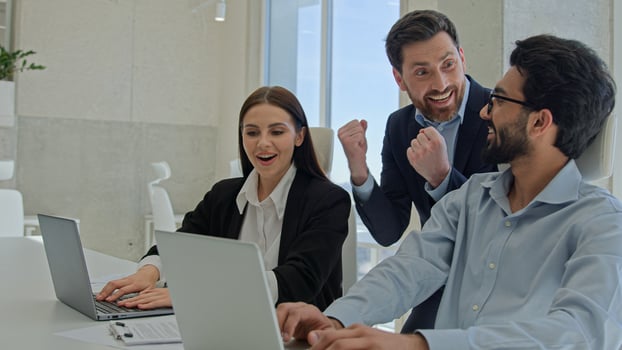 Happy creative team celebrate victory in office successful sales stock market data online business people businessmen and businesswoman winning teambuilding corporate teamwork with documents laptop photo