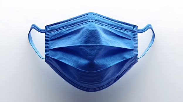 Simple blue surgical mask illustration floats against pure white background. Clean design emphasizes medical protection with subtle shadow beneath disposable face covering. essential photo